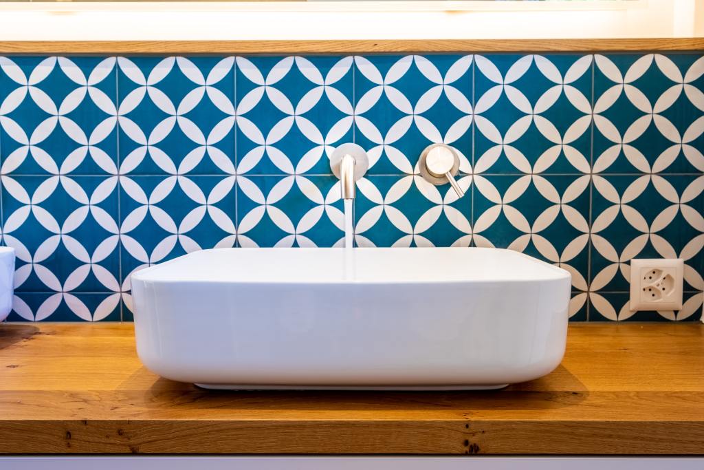 Blue and white patterned tile backdrop by a modern sink basin
