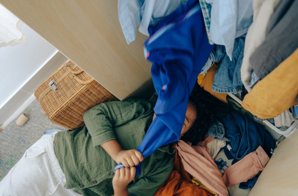 A woman in a green shirt lying in a pile of messy clothes