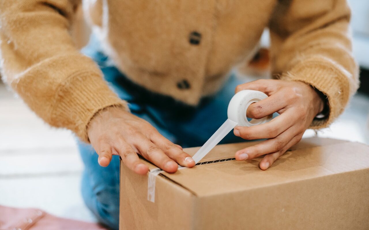 A person sealing a cardboard box