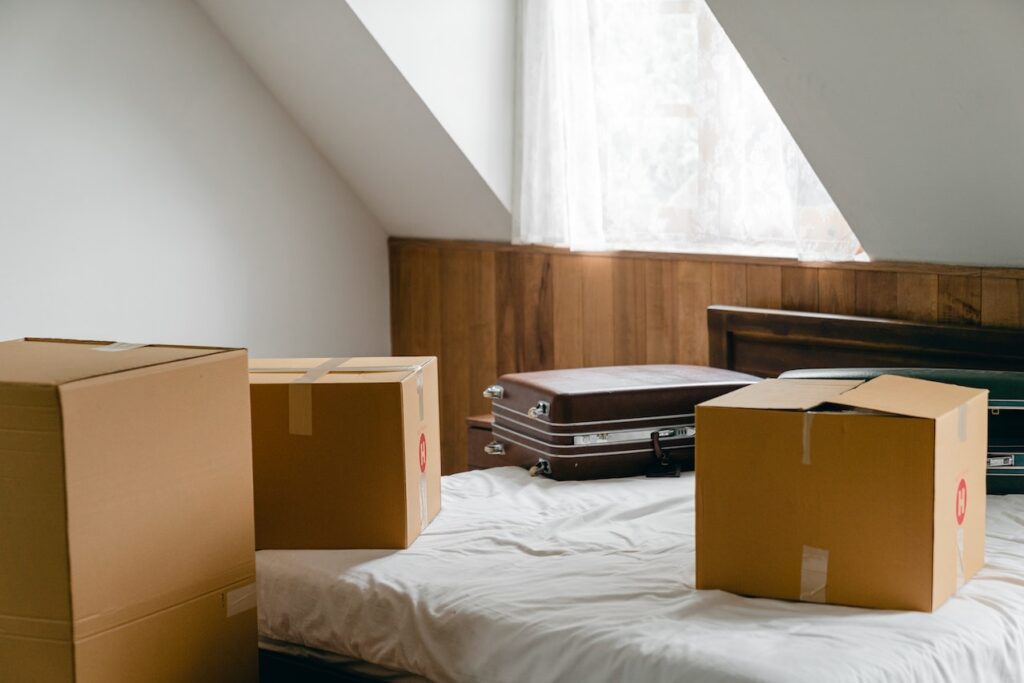 Moving boxes and a suitcase on a bed.