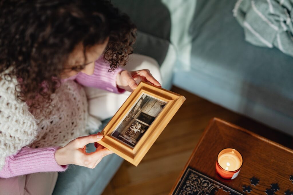 A woman is admiring an old photo in a wooden frame.