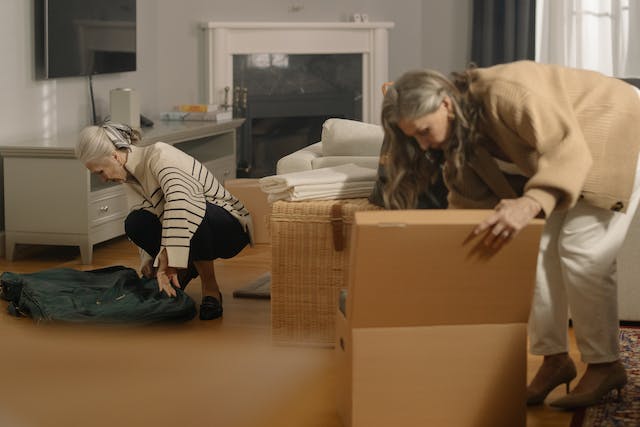 Two women pack their things into cardboard boxes

